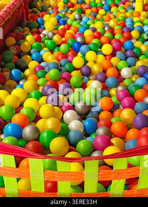 Balles en plastique colorées remplissant une pataugeoire pour enfants dans un parc de jeux intérieur. Des sphères multicolores vives créant un arrière-plan vibrant en plein cadre avec Banque D'Images