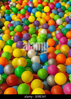 Balles en plastique colorées remplissant une pataugeoire pour enfants dans un parc de jeux intérieur. Des sphères multicolores vives créant un arrière-plan vibrant en plein cadre avec Banque D'Images