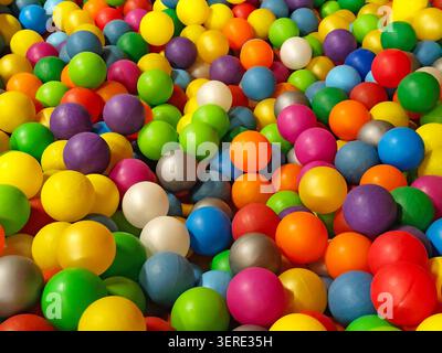 Balles en plastique colorées remplissant une pataugeoire pour enfants dans un parc de jeux intérieur. Des sphères multicolores vives créant un arrière-plan vibrant en plein cadre avec Banque D'Images