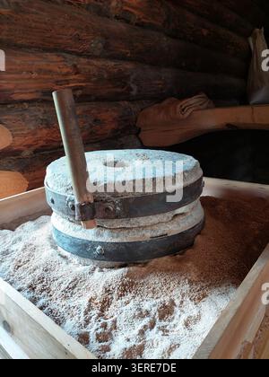 Requête traditionnelle en pierre ancienne pour broyer le grain en farine dans un intérieur rustique en bois. Banque D'Images