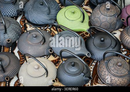 Une vue rapprochée de haut en bas révèle une collection de théières traditionnelles en fonte, souvent appelées tetsubin, dans diverses teintes sombres, une vert citron, et certaines Banque D'Images
