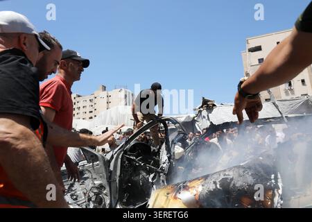 Les Palestiniens se rassemblent sur le site de la grève meurtrière de véhicules dans la ville de Gaza les Palestiniens et le personnel de la défense civile se rassemblent autour d’un véhicule détruit qui a été pris pour cible lors d’une frappe aérienne israélienne dans la ville de Gaza, le 18 juin 2026. La frappe a tué trois Palestiniens, selon des sources médicales, et a causé d'importants dégâts au véhicule. Photo de Belal Osama apaimages Gaza bande de Gaza territoire palestinien 180626 Gaza BO 1 0020 Copyright : xapaimagesxBelalxOsamaxxapaimagesx Banque D'Images