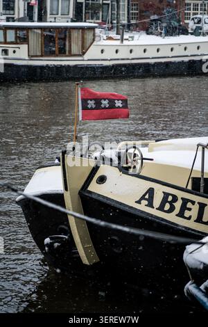 Un gros plan du bateau sur le canal nommé « Abel » est vu lors d'une journée d'hiver enneigée à Amsterdam, aux pays-Bas, avec sa proue couverte de neige. Le bateau promine Banque D'Images
