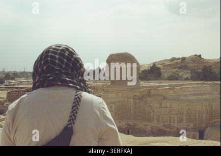 Photographie de film 35mm d'une personne vue de derrière, portant un foulard noir et blanc en keffiyeh avec une queue tressée, regardant vers le Grand Sphi Banque D'Images