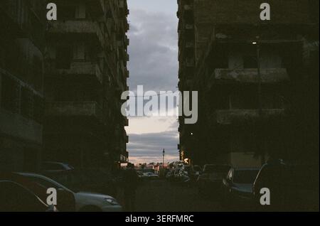 Une photographie au crépuscule regardant vers le bas d'un étroit canyon urbain à Alexandrie, en Égypte. Les grands immeubles d'appartements des deux côtés sont rendus en quasi-silh Banque D'Images
