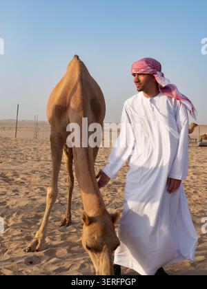 Homme en robe traditionnelle de kandura blanc couché sur une dune de sable dans le désert arabe. Photographie commerciale conceptuelle de relaxation. Banque D'Images