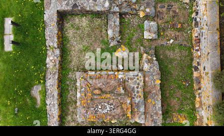 Un plan au-dessus de ruines de fondation en pierre moussue avec de l'herbe et du lichen jaune. Banque D'Images