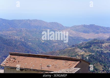 Toit en tuiles de terre cuite surplombant les vastes montagnes de l'Aspromonte et la mer Ionienne de Bova, parc national de l'Aspromonte, Calabre du sud de l'Italie. Banque D'Images