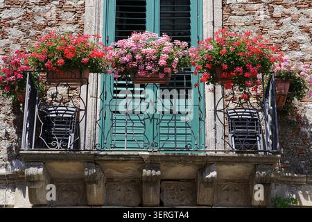 Beau balcon débordant de fleurs roses sur un bâtiment traditionnel en pierre dans le village historique de Bova, parc national d'Aspromonte, Calabre Sout Banque D'Images