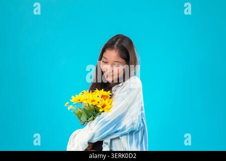 Jeune femme tenant un bouquet de fleurs jaunes Banque D'Images