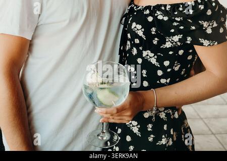 Couple apprécie les boissons et narguilé dans un cadre extérieur lumineux avec des plantes lors d'un week-end de rassemblement. l'homme et la femme se tiennent proches l'un de l'autre, appréciant le drin Banque D'Images