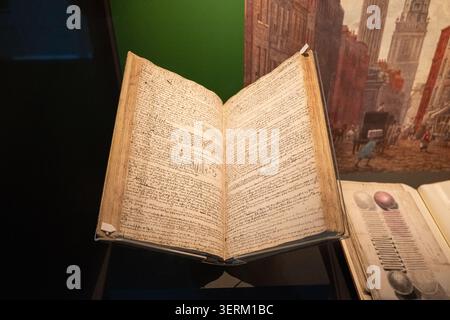 Londres, Royaume-Uni - 17 mars 25 : livre ouvert écrit à la main dans une vitrine en verre, photographié dans un cadre de musée à la Guildhall Art Gallery, ville de Londo Banque D'Images