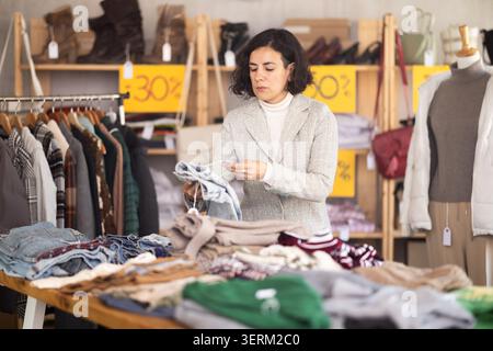 Elégance femme client choisissant soigneusement un pantalon de jeans élégant dans le magasin de vêtements Banque D'Images