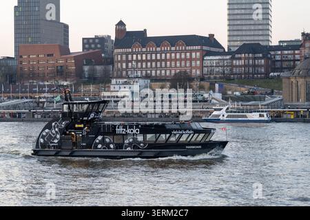 Hambourg, Allemagne - 28 février 25 : ferry de passagers traversant l'Elbe dans le port de Hambourg avec des bâtiments en bord de mer en arrière-plan, Allemagne. Banque D'Images