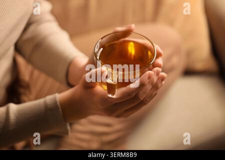 Chaleur confortable et détente avec du thé chaud dans les mains, boisson réconfortante pour le bien-être et l'auto-soin à la maison Banque D'Images