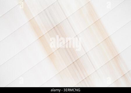 Un fond abstrait avec un motif de rayures diagonales dans des tons doux pêche et neutres, créant une esthétique épurée et minimaliste. Banque D'Images