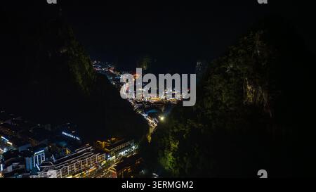 Guilin, Chine - 16 juin 2026 : vue aérienne de la ville illuminée de Yangshuozhen nichée entre les sommets sombres des montagnes karstiques la nuit avec la ville lumineuse Banque D'Images