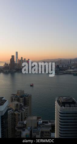 Hong Kong - 14 février 2026 : vue aérienne des gratte-ciels du port Victoria et d'une jonque traditionnelle à voile rouge au coucher du soleil à Hô Banque D'Images