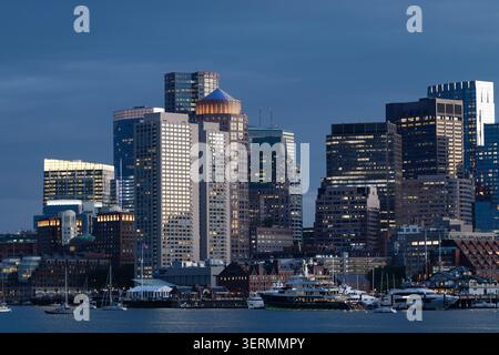 Horizon du centre-ville de Boston à travers le port de Boston à la tombée de la nuit, Massachusetts. Banque D'Images