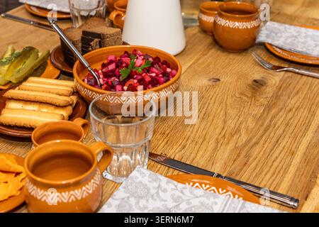 Repas lituanien traditionnel avec salade de betteraves, pain de seigle et cornichons servis sur une table rustique en bois dans une salle à manger traditionnelle. Banque D'Images
