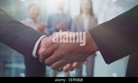 Gros plan deux hommes d'affaires multiethniques serrant la main au soleil au bureau trois collègues de diversité félicitent. Des hommes d'affaires multiraciaux méconnaissables Banque D'Images