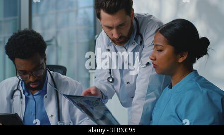 Équipe médicale groupe de médecins discutant de médecine rayons X analyse diagnostic prescription de santé parler à la réunion dans la clinique hospitalière. Multiethnique Banque D'Images
