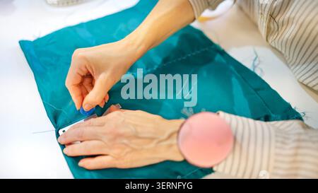 Femme marquant le tissu avec la craie de tailleur dans l'atelier de couture Banque D'Images