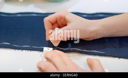 Mains marquant le tissu avec de la craie dans un atelier de couture Banque D'Images