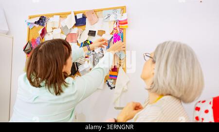 Femmes recherchant des échantillons de tissu sur une planche d'humeur de couture Banque D'Images