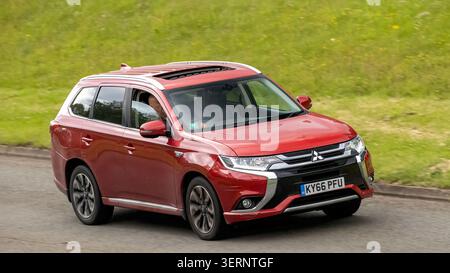 Milton Keynes,Bucks,UK - 17 juin 2026 : 2016 rouge Mitsubishi Outlander hybride SUV électrique conduisant sur une route britannique Banque D'Images
