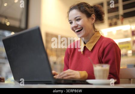 Jeune femme joyeuse riant de son ordinateur portable Banque D'Images