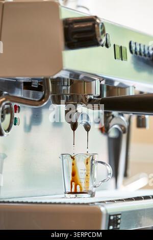 Espresso extrait d'une machine à café professionnelle dans des tasses en verre, vue rapprochée du processus de préparation du café dans un café Banque D'Images