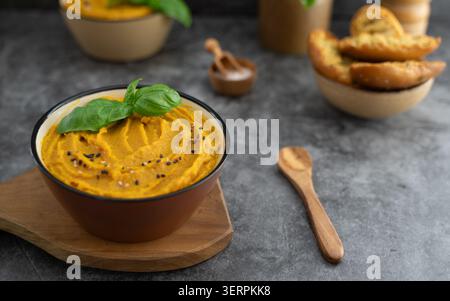 Gros plan de soupe de citrouille maison servie dans un bol rustique avec des feuilles de basilic frais Banque D'Images