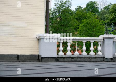 Un balcon serein surplombe des arbres verdoyants sous un ciel nuageux. Banque D'Images