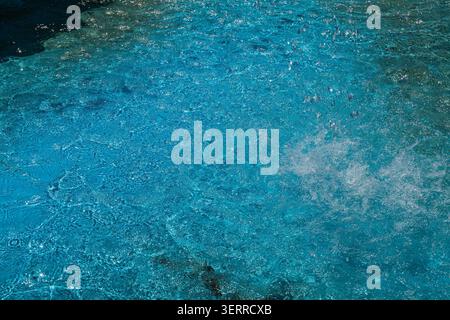 Éclaboussure d'eau bleue vibrante avec de nombreuses gouttelettes et ondulations, mettant en valeur l'énergie et la fluidité, avec un éclairage lumineux et une surface texturée, captur Banque D'Images