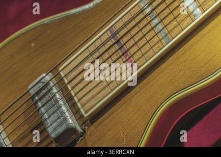 Cou de guitare acoustique et touche, présentant des motifs de grain de bois léger, marqueurs incrustés, finition lisse, frettes usées, fond de tissu rouge, highlighti Banque D'Images