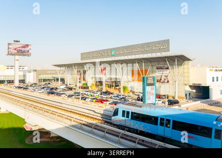 Dubaï, Émirats arabes Unis - 25 octobre 2025 : train moderne sans conducteur sur la voie surélevée du métro de Dubaï. Entrée du centre commercial Dubai Times Square Center, façade vitrée et Banque D'Images