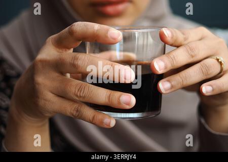 Femme tenant un verre de boissons gazeuses dans ses mains Banque D'Images
