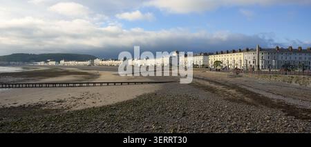 La promenade victorienne historique et la plage de galets de Llandudno, au nord du pays de Galles, balaient vers le promontoire lointain sous un ciel bleu et nuageux spectaculaire. Banque D'Images
