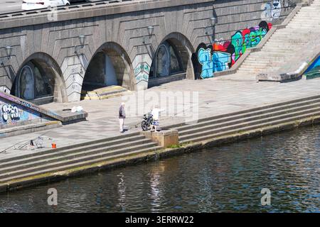 Deux pêcheurs se tiennent près de la rivière, jetant des lignes sous la lumière du soleil. Kiev, Ukraine 19 juin 2026 Banque D'Images