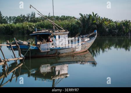 Vieux bateau de pêche en bois vieilli flottant sur une rivière tropicale calme Banque D'Images