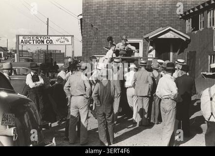 Photographie historique de Russell Lee montrant un groupe de fermiers rassemblés lors d'une vente aux enchères de pêches devant la Sikeston Auction Company à Sikeston, Missouri, mai 1938. Banque D'Images