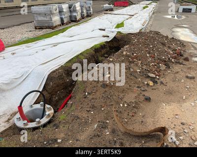 Chantier de construction de routes, tranchée ouverte, ligne d'utilité souterraine, revêtement géotextile, matériaux de pavage pour les travaux d'infrastructure en zone urbaine. Civil Banque D'Images