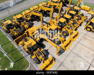 De nouveaux tracteurs et pelles hydrauliques stationnés chez un concessionnaire de machines de construction. Banque D'Images