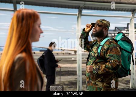 Soldat de l'armée marchant dans l'aéroport, piste d'avion et tour de contrôle visible sur la fenêtre en arrière-plan. Homme afro-américain à l'aéroport finissant son service militaire, rentrant chez lui Banque D'Images