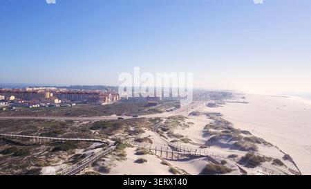 Une vaste perspective aérienne capture les dunes lumineuses et sablonneuses de la plage de Torreira et de la ville côtière adjacente. La scène présente natura douce et brumeuse Banque D'Images