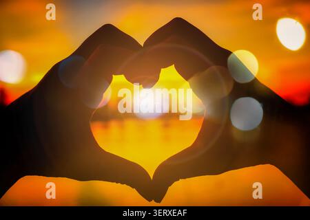 Silhouette d'amour forme de main dans le soir coucher de soleil concept de valentines jour. Banque D'Images