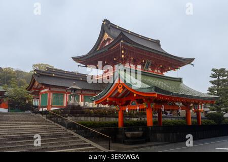 Kyoto, Japon - 10 avril 2026 : une geisha avec un unbrella sur un escalier du sanctuaire shinto Fushimi Inari-taisha sous la pluie Banque D'Images