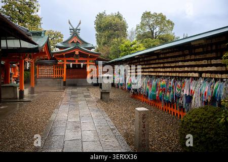 Kyoto, Japon - 10 avril 2026 : Ema Wood Wish plaques et bandes senbazuru sur un mur dans le sanctuaire shinto Fushimi Inari-taisha Banque D'Images