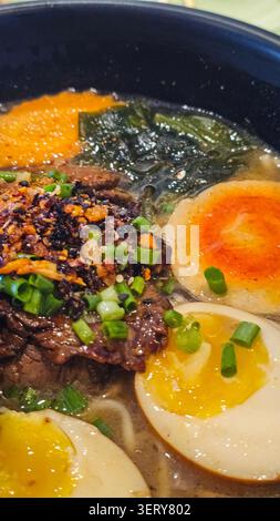 Délicieux ramen japonais avec bœuf, œufs à la coque, algues nori, champignons et oignons verts frais dans un bouillon savoureux. Soupe de nouilles asiatique traditionnelle Banque D'Images